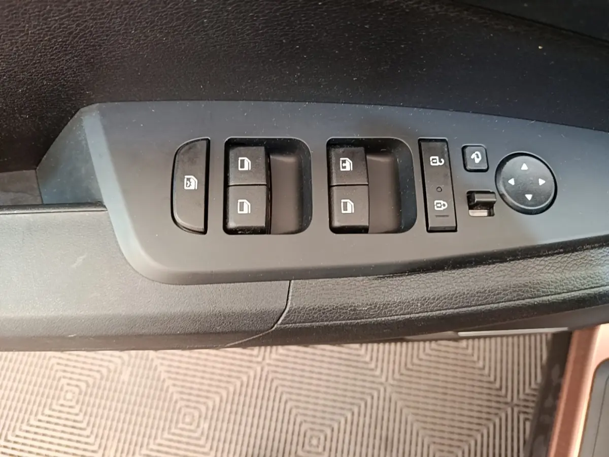 Gros plan sur les commandes de lève-vitres et rétroviseurs côté conducteur du Kia Sportage beige 2022.