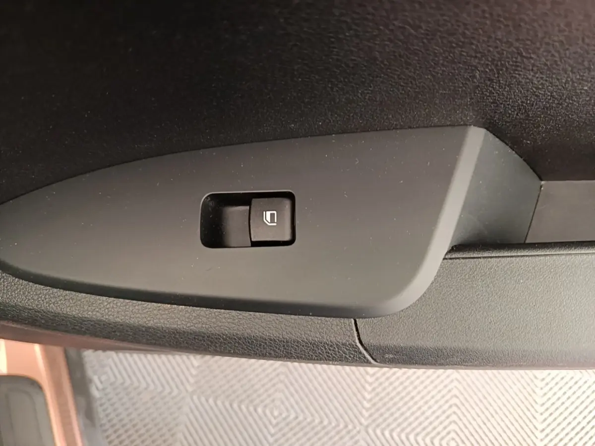 Bouton de verrouillage des vitres sur la porte intérieure noire d’un KIA SPORTAGE beige, vue en gros plan.
