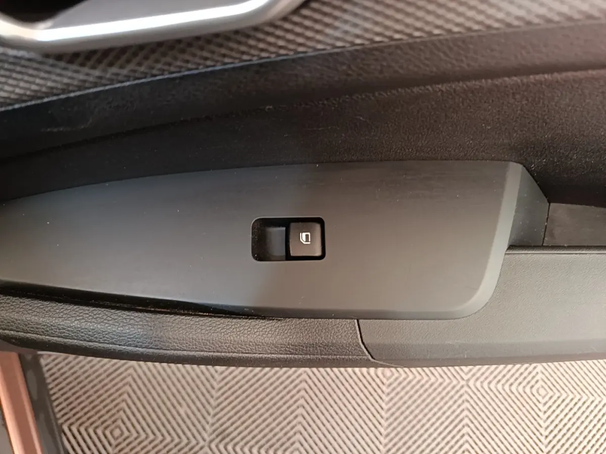 Gros plan sur le bouton de verrouillage électrique des vitres sur la porte intérieure côté conducteur du Kia Sportage beige 2022.
