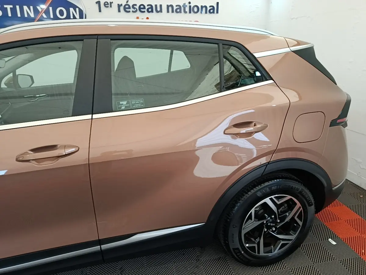 Vue côté droit arrière du KIA SPORTAGE beige 2022 avec jante alliage et poignées de porte assorties.