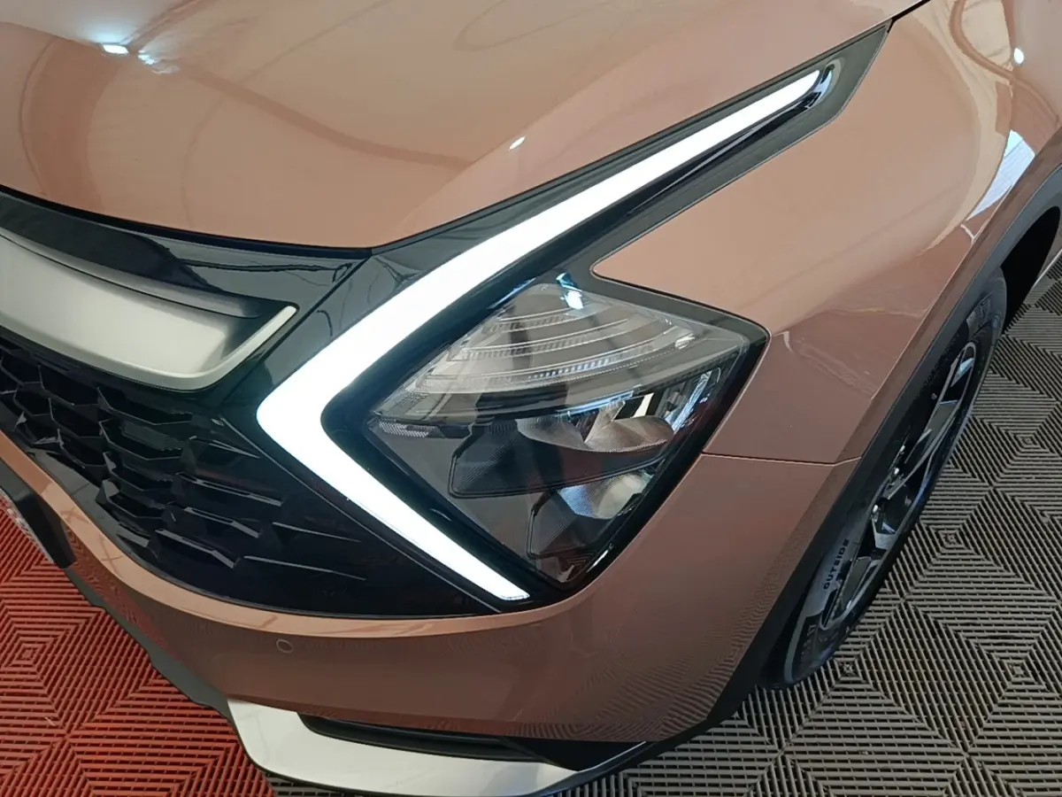 Gros plan sur l'avant droit beige du KIA Sportage 2022, mettant en valeur le phare LED en forme de boomerang.