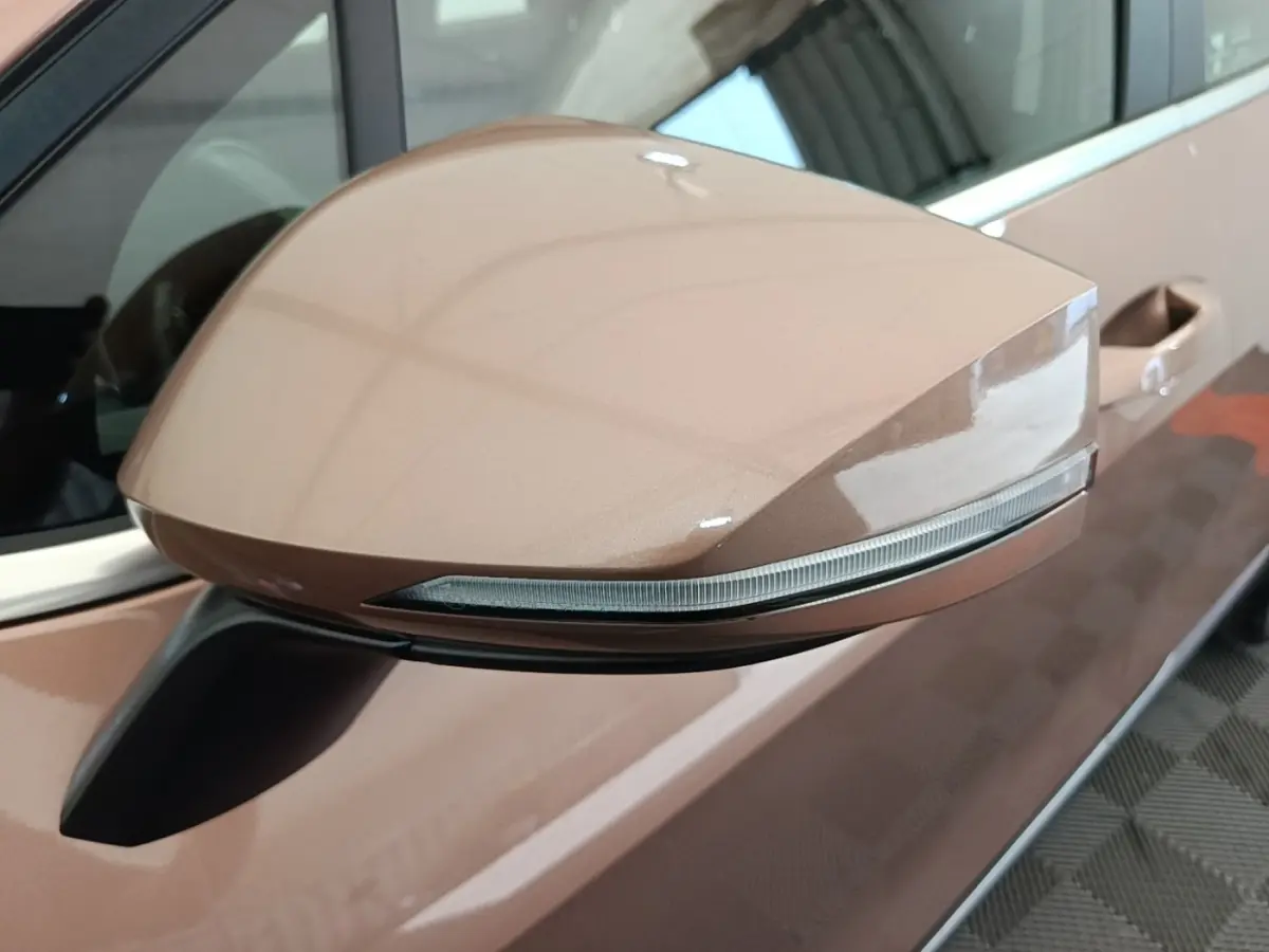 Rétroviseur côté conducteur beige du Kia Sportage 2022 avec clignotant intégré, vu en gros plan depuis l'avant gauche.