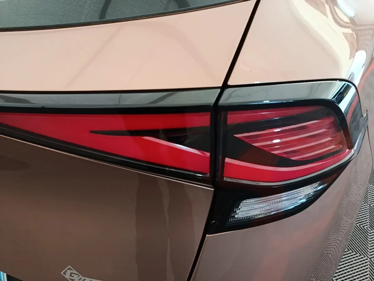 Gros plan sur le feu arrière droit rouge et blanc d’un KIA SPORTAGE beige 2022, soulignant ses lignes modernes.