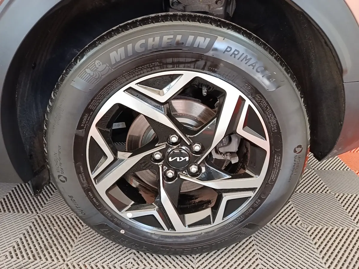 Gros plan sur la roue avant droite d’un KIA Sportage beige, jante alliage noire et argent avec pneu Michelin.