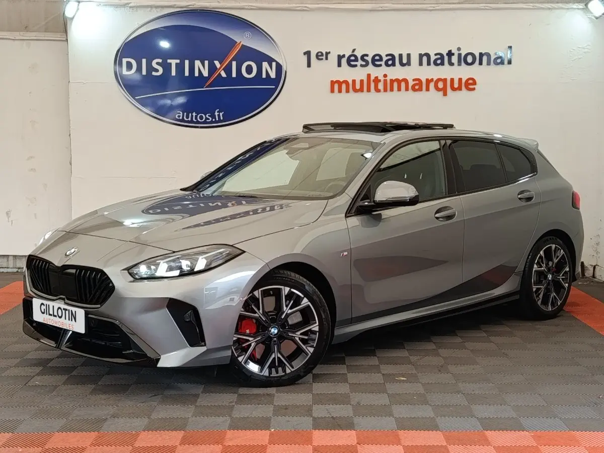 BMW Série 1 120 DKG7 M Sport gris clair vue 3/4 avant droit avec jantes noires et étriers rouges visibles
