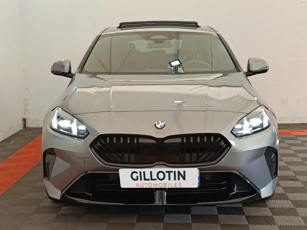 Vue avant d'une BMW Série 1 120 DKG7 M Sport gris clair avec phares LED allumés et calandre noire distinctive.