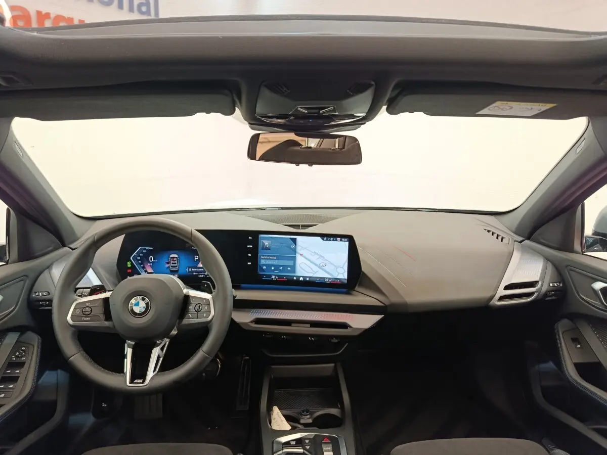 Vue intérieure avant de la BMW Série 1 120 DKG7 M Sport 2025, tableau de bord numérique et écran tactile central.