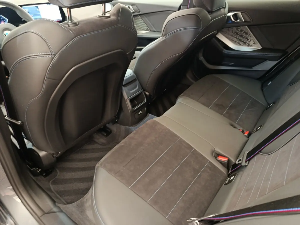 Vue intérieure arrière côté droit de la BMW Série 1 120 DKG7 M Sport 2025 avec sièges en cuir et alcantara noirs.