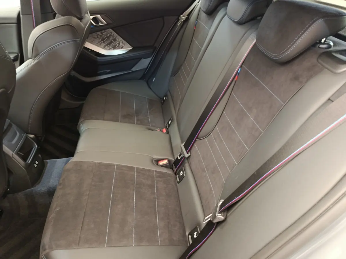 Vue intérieure côté droit sur la banquette arrière en cuir et alcantara gris foncé avec surpiqûres tricolores BMW M Sport.