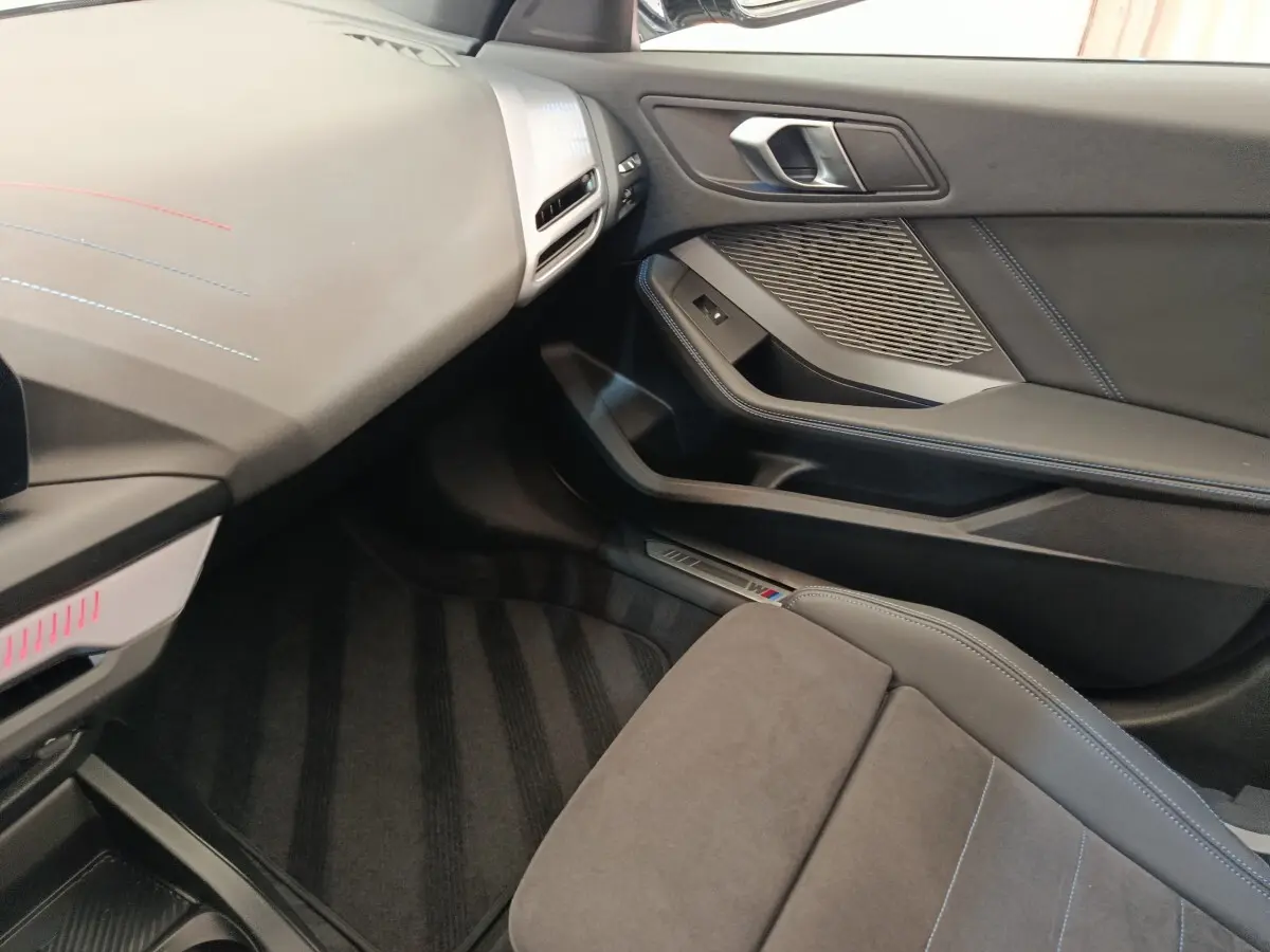 Intérieur côté passager de la BMW Série 1 120 DKG7 M Sport 2025, avec sellerie grise et finitions M Sport visibles.
