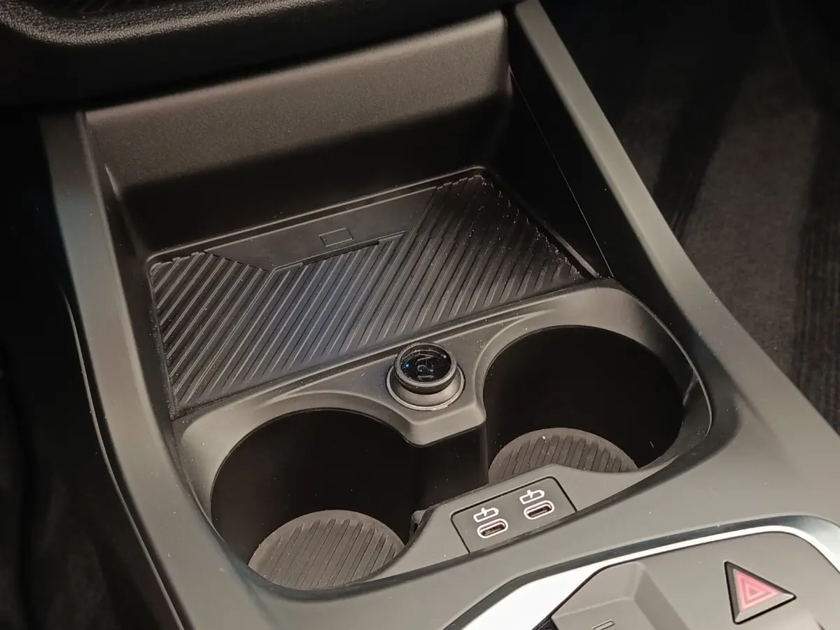 Gros plan sur la console centrale noire de la BMW Série 1 120 DKG7 M Sport avec porte-gobelets et prises USB.