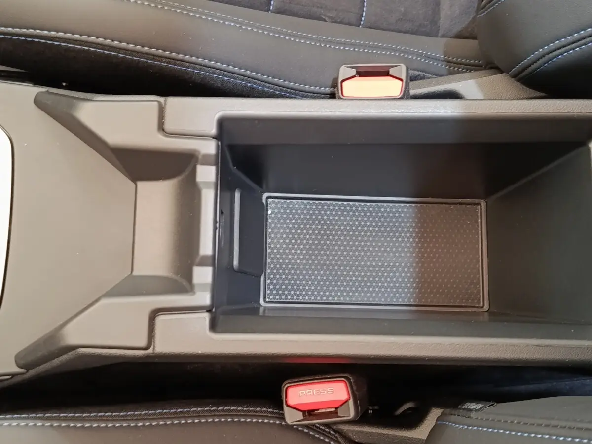 Vue plongeante sur le rangement central intérieur de la BMW Série 1 120 DKG7 M Sport 2025, avec sièges noirs et ceintures rouges.