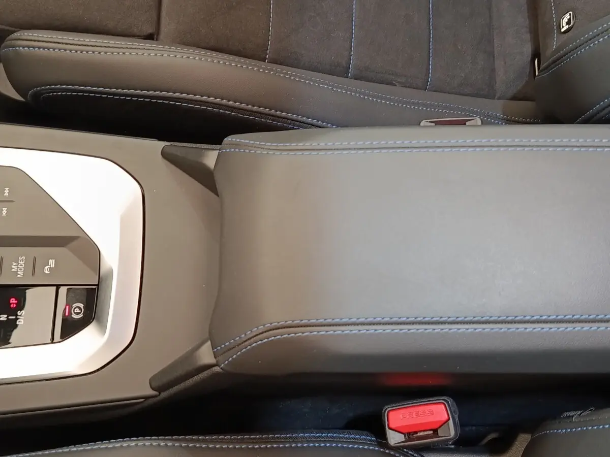 Vue rapprochée de la console centrale et accoudoir en cuir noir avec surpiqûres bleues de la BMW Série 1 120 DKG7 M Sport.