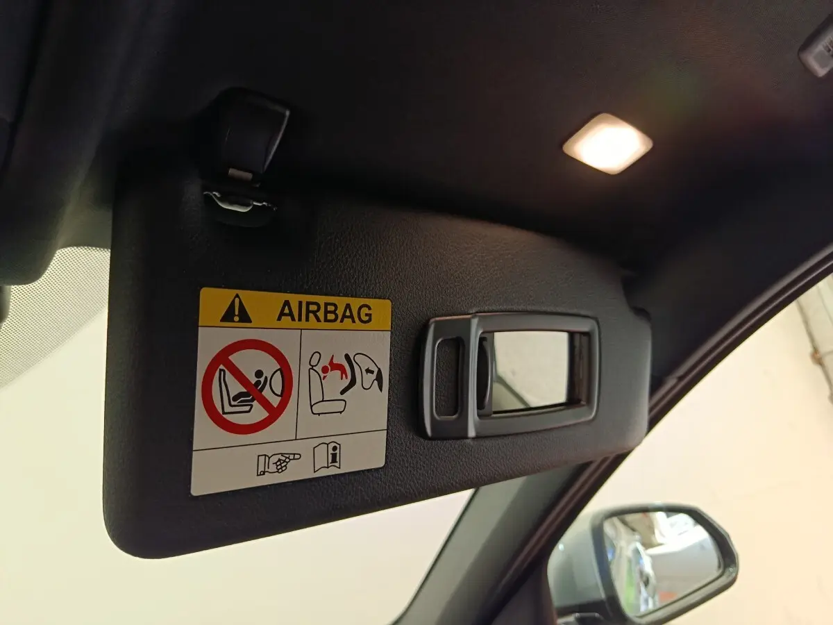 Détail du pare-soleil côté conducteur avec miroir intégré et avertissement airbag dans une BMW Série 1 gris clair.