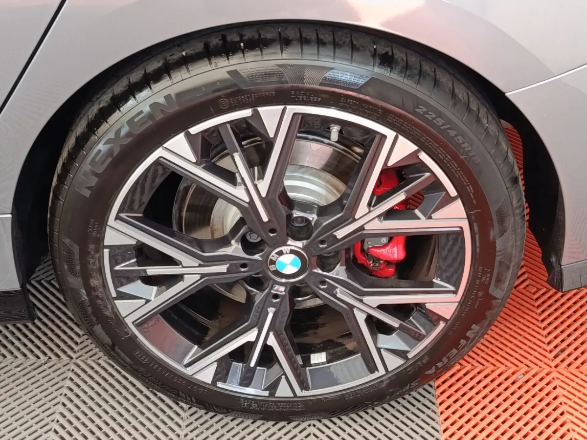 Gros plan sur la roue avant droite d'une BMW Série 1 120 DKG7 M Sport gris clair avec étrier de frein rouge.