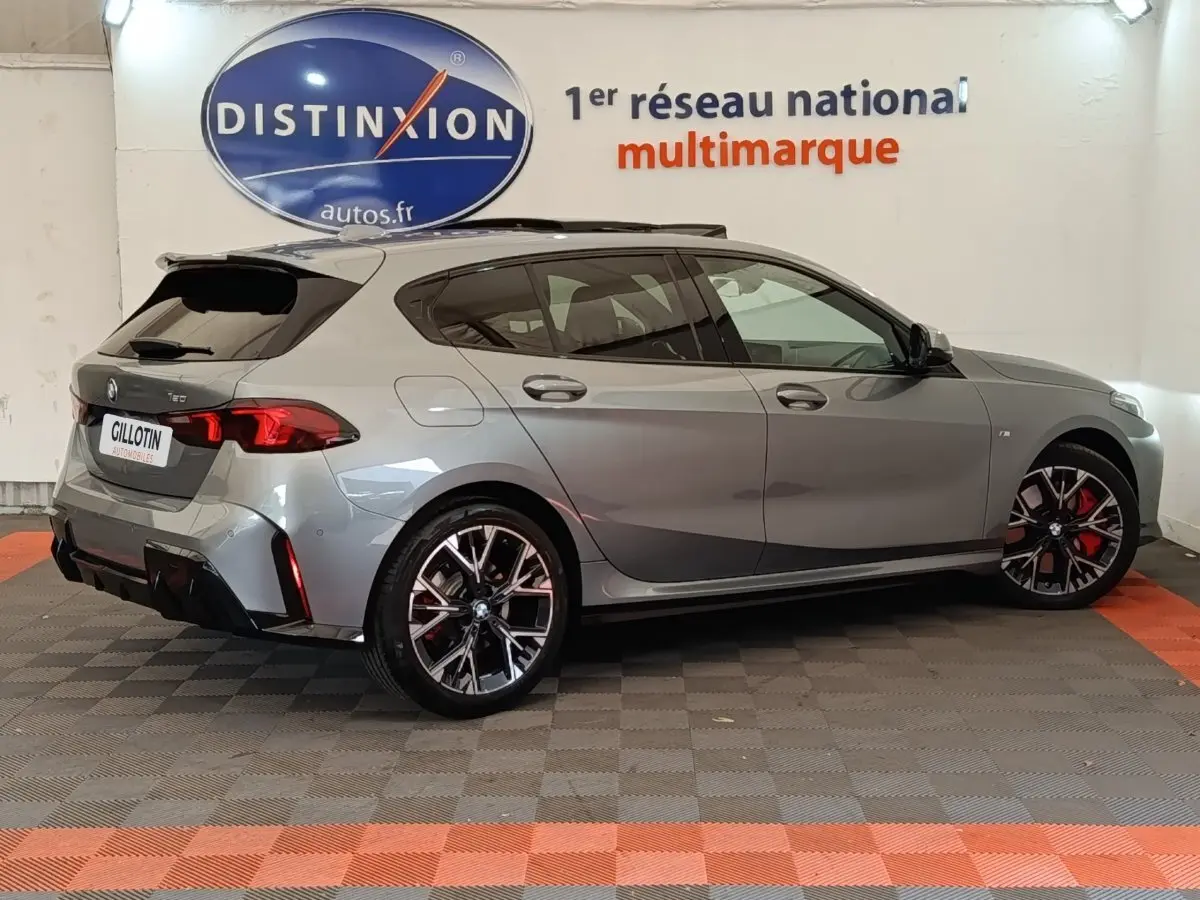 BMW Série 1 120 DKG7 M Sport gris clair vue de profil droit, avec jantes noires et étriers rouges visibles.