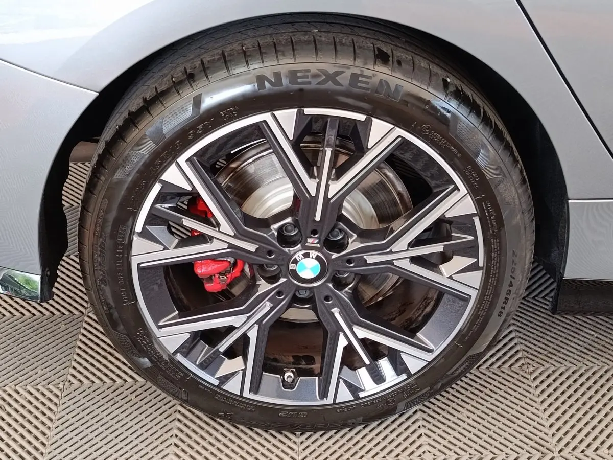 Gros plan sur la roue avant gauche gris clair d'une BMW Série 1 120 DKG7 M Sport avec étrier de frein rouge.