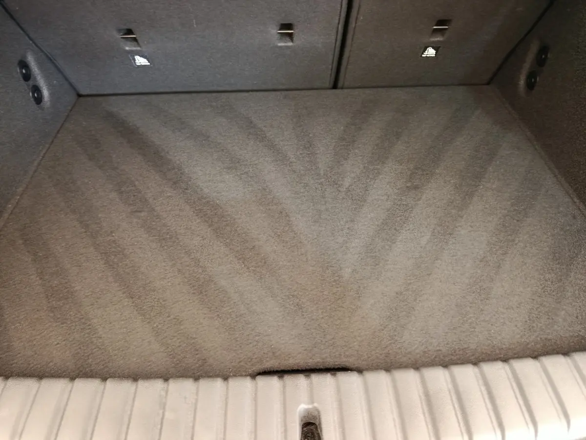 Coffre vide en moquette grise de BMW Série 1 120 DKG7 M Sport, vue intérieure depuis l'ouverture arrière.