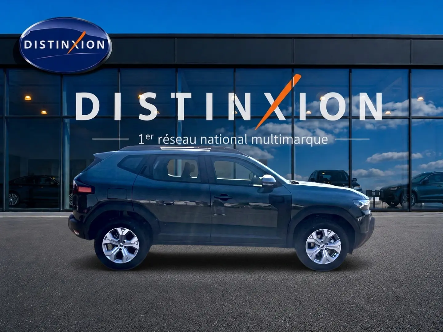 Profil côté gauche du Dacia Duster 2026 en kaki lichen, avec jantes alu et rétroviseurs chromés devant une vitrine Distinxion.