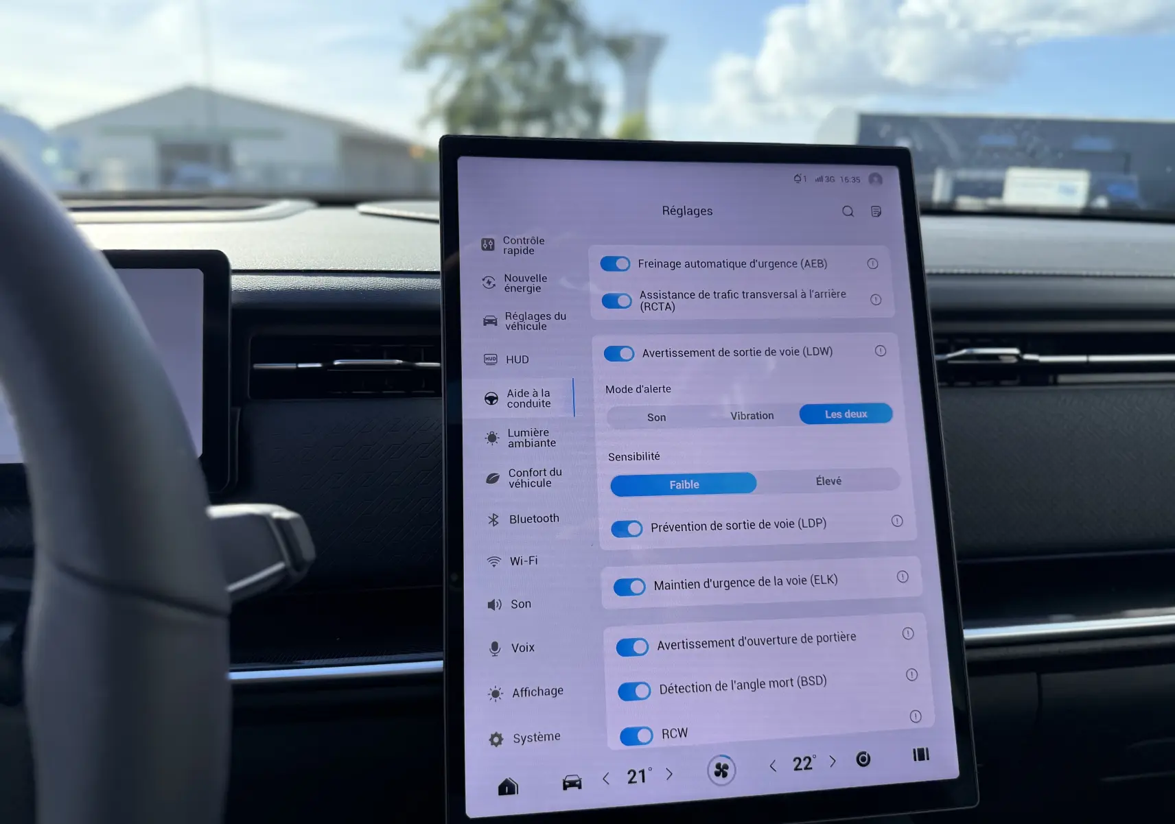 Vue intérieure centrée sur l’écran tactile vertical du tableau de bord du JAECOO J7 PHEV gris olive, affichant les réglages d’aide à la conduite.