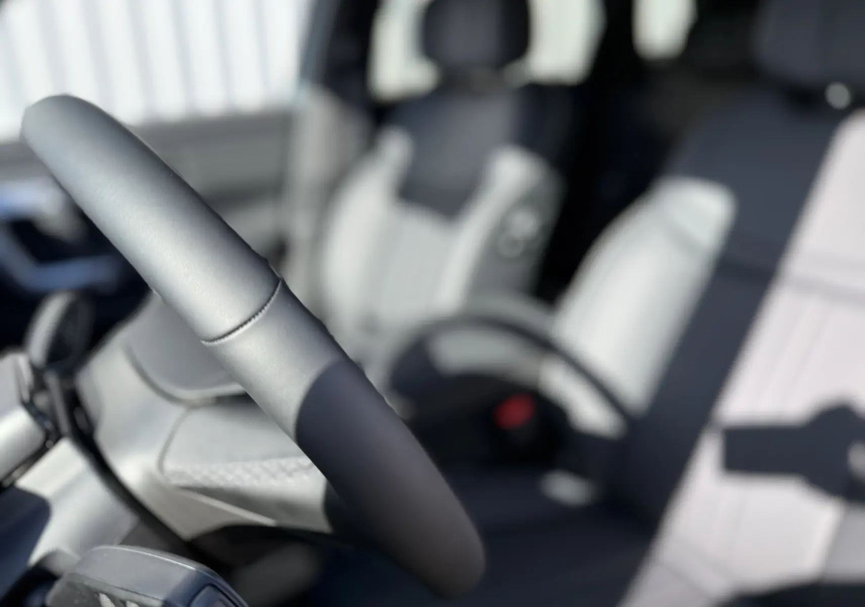 Gros plan sur le volant et siège avant gris clair de la JAECOO J7 PHEV 279 CH SHS-P EXCLUSIVE, intérieur moderne.