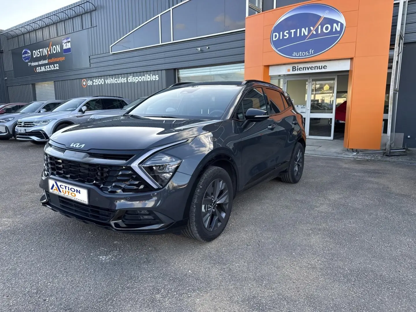 KIA Sportage gris Eclipse métallisé vu en 3/4 avant droit devant un garage Distinxion.