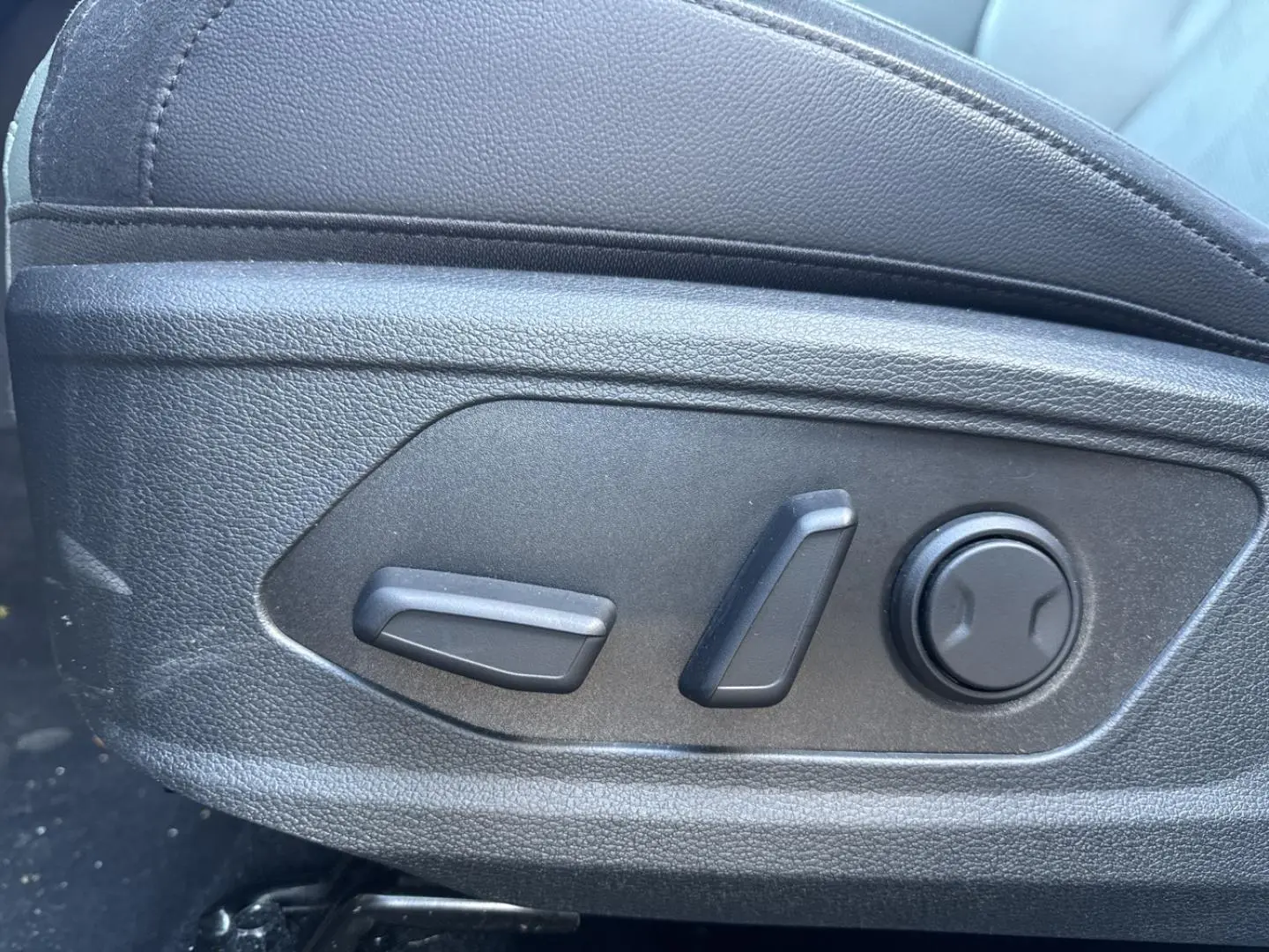 Gros plan sur les commandes de réglage électrique du siège conducteur noir dans un KIA SPORTAGE gris Eclipse Métallisée 2025.