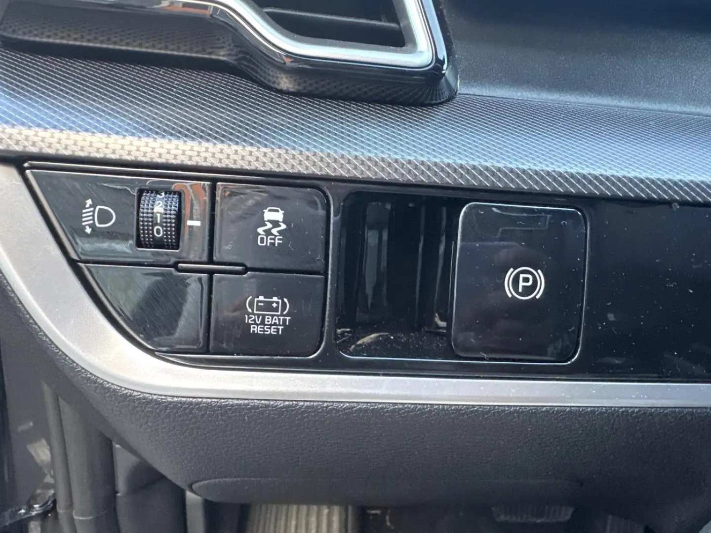 Détail des commandes de tableau de bord noir et gris dans un Kia Sportage 2025 hybride.