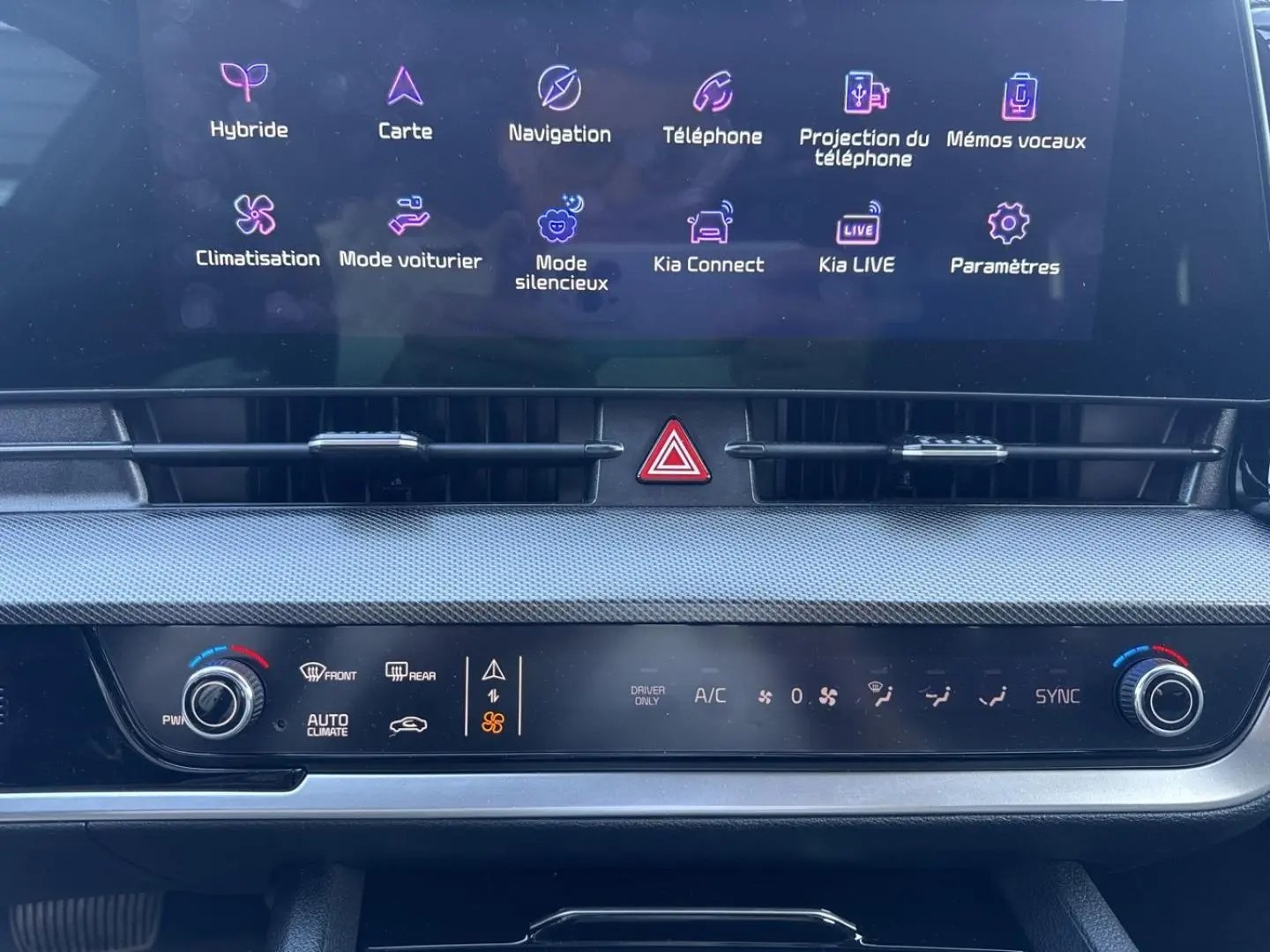 Vue rapprochée de la console centrale du Kia Sportage 2025, écran tactile affichant les options connectées et climatisation automatique.