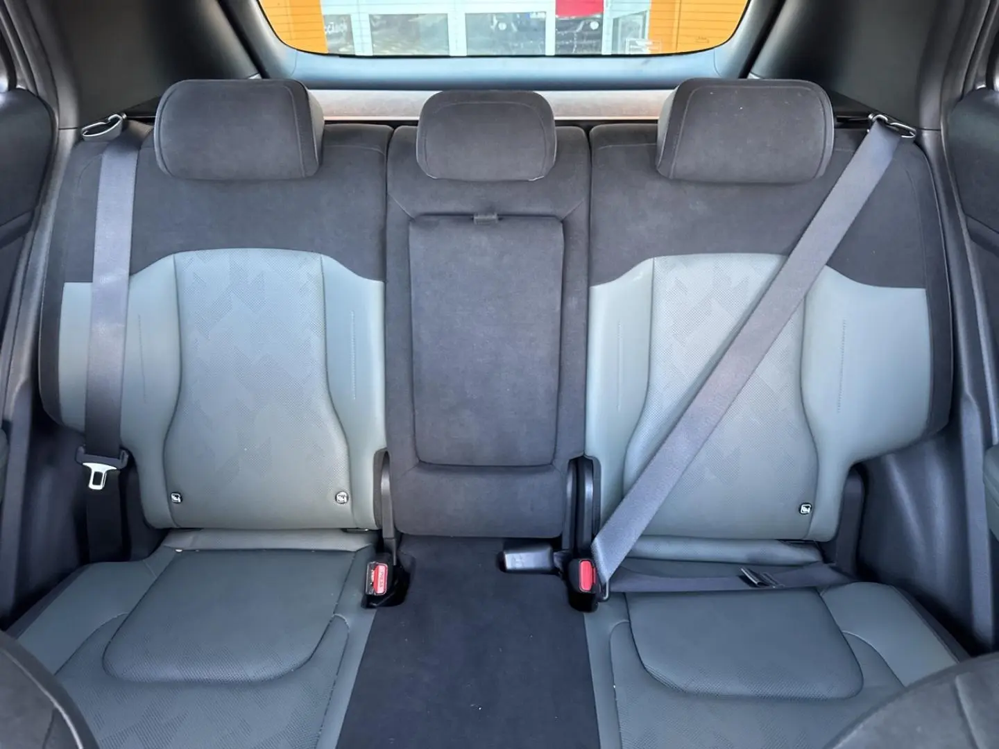 Vue arrière intérieure du Kia Sportage 2025 montrant la banquette 3 places en cuir suédine vert pin et gris clair.