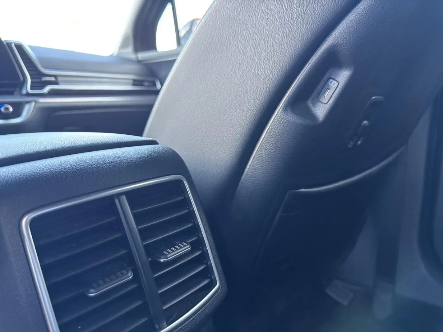Détail de la console arrière et siège en cuir noir à l'intérieur du Kia Sportage 2025, version hybride.
