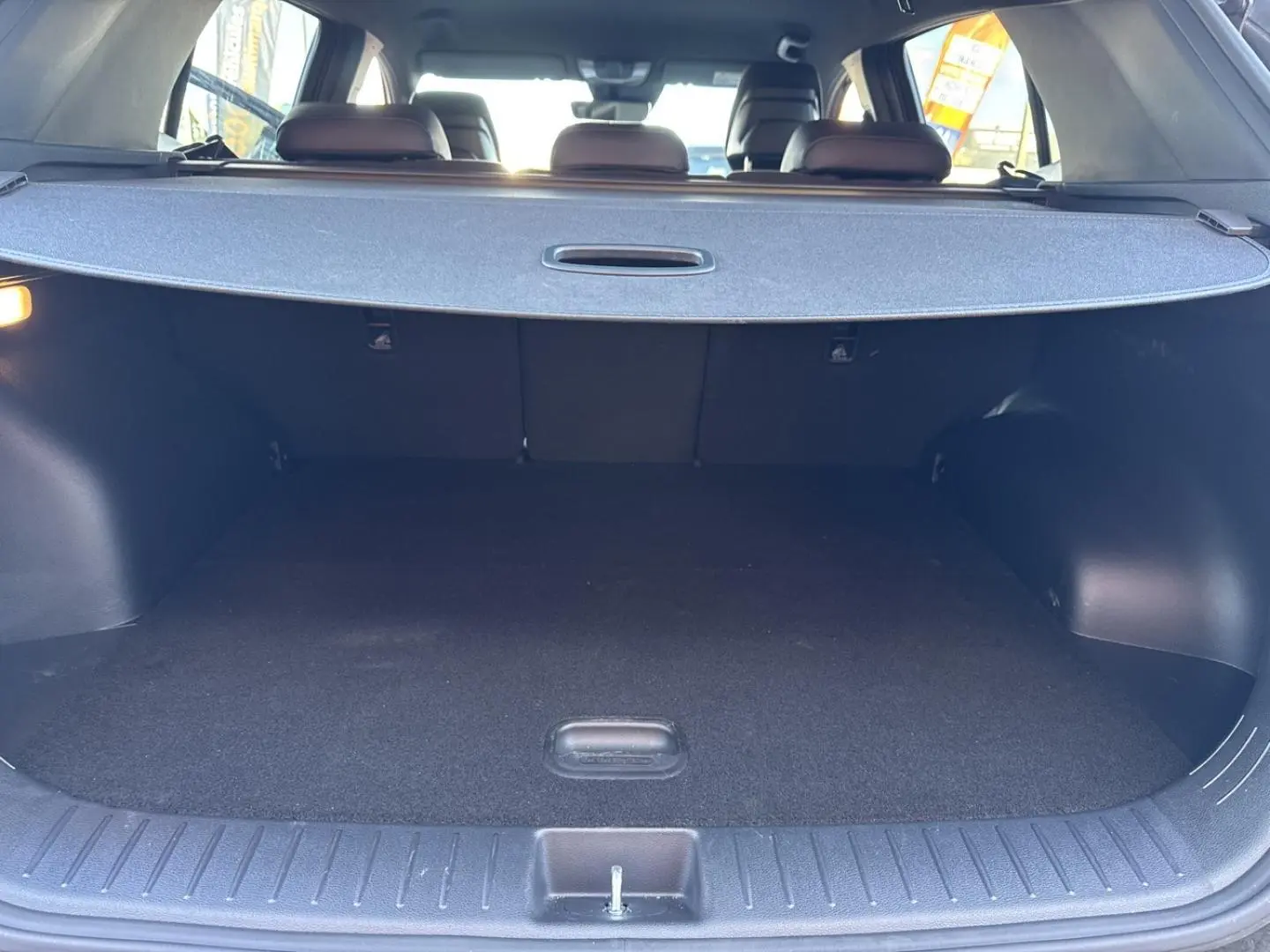 Coffre ouvert vu de l’arrière d’un KIA Sportage gris Eclipse avec cache-bagages déployé et banquette arrière visible.