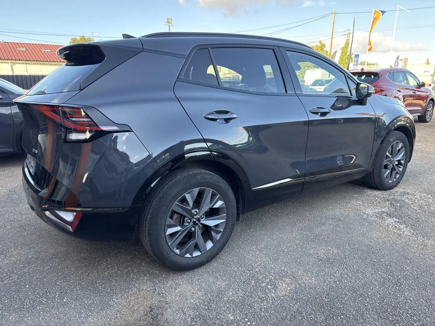 KIA Sportage gris Eclipse métallisé vu en 3/4 arrière droit, avec jantes alliage et feux arrière LED distinctifs.