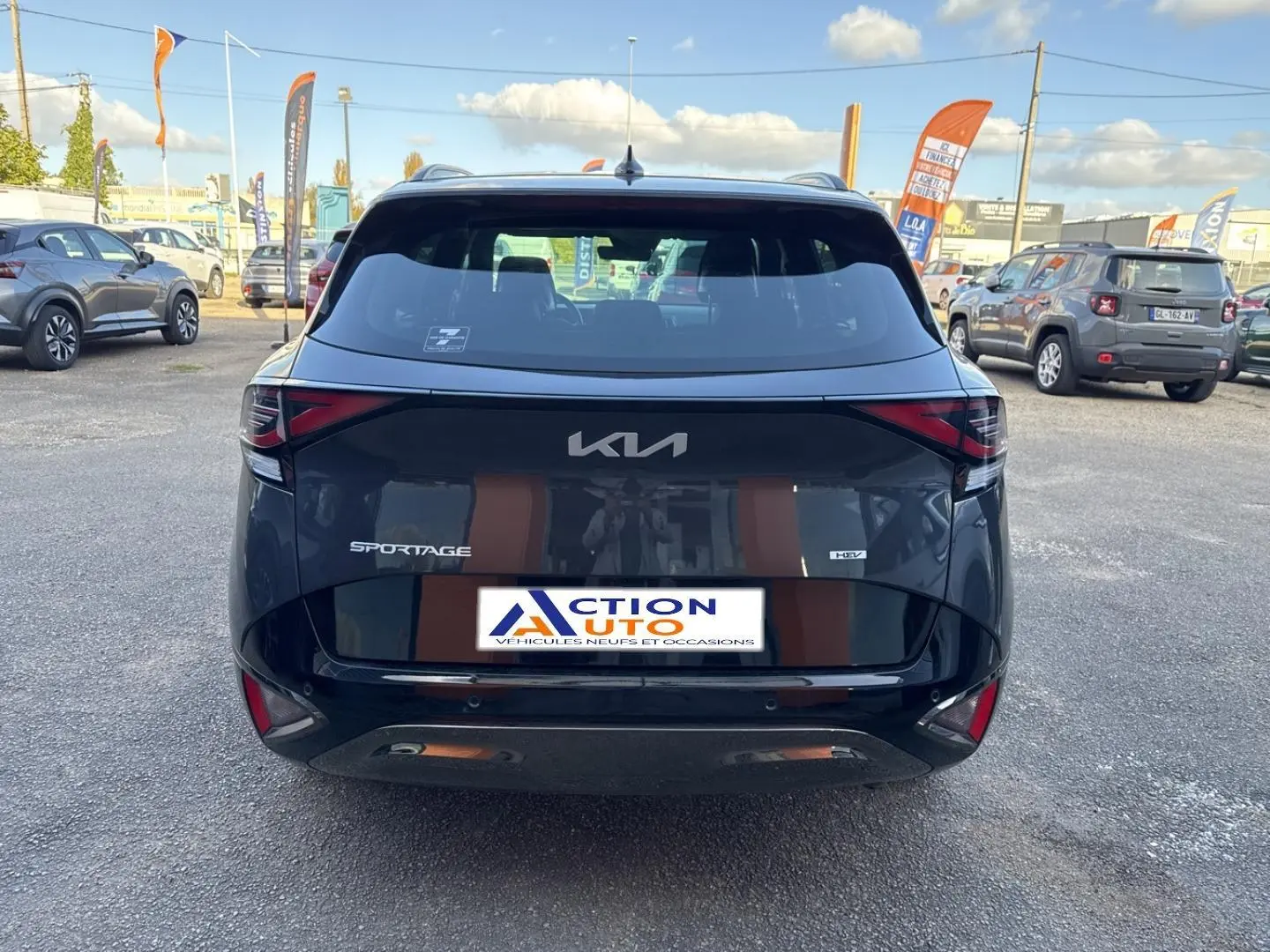 Vue arrière d'un KIA Sportage gris Eclipse métallisé 2025 avec feux LED et logo central sur un parking extérieur.