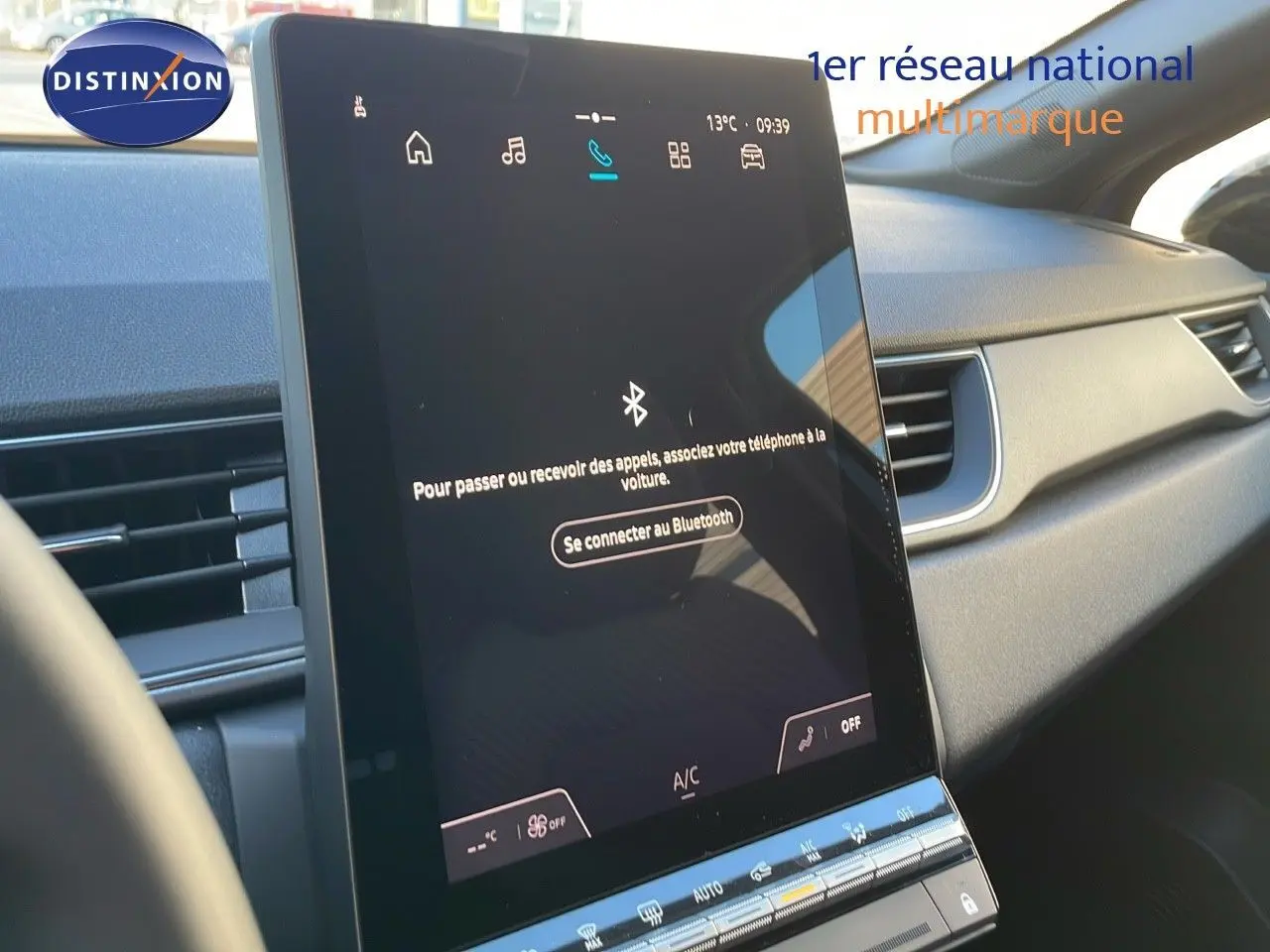 Écran tactile central du tableau de bord du Renault Captur bleu Iron Metal avec toit noir, vue intérieure côté passager.