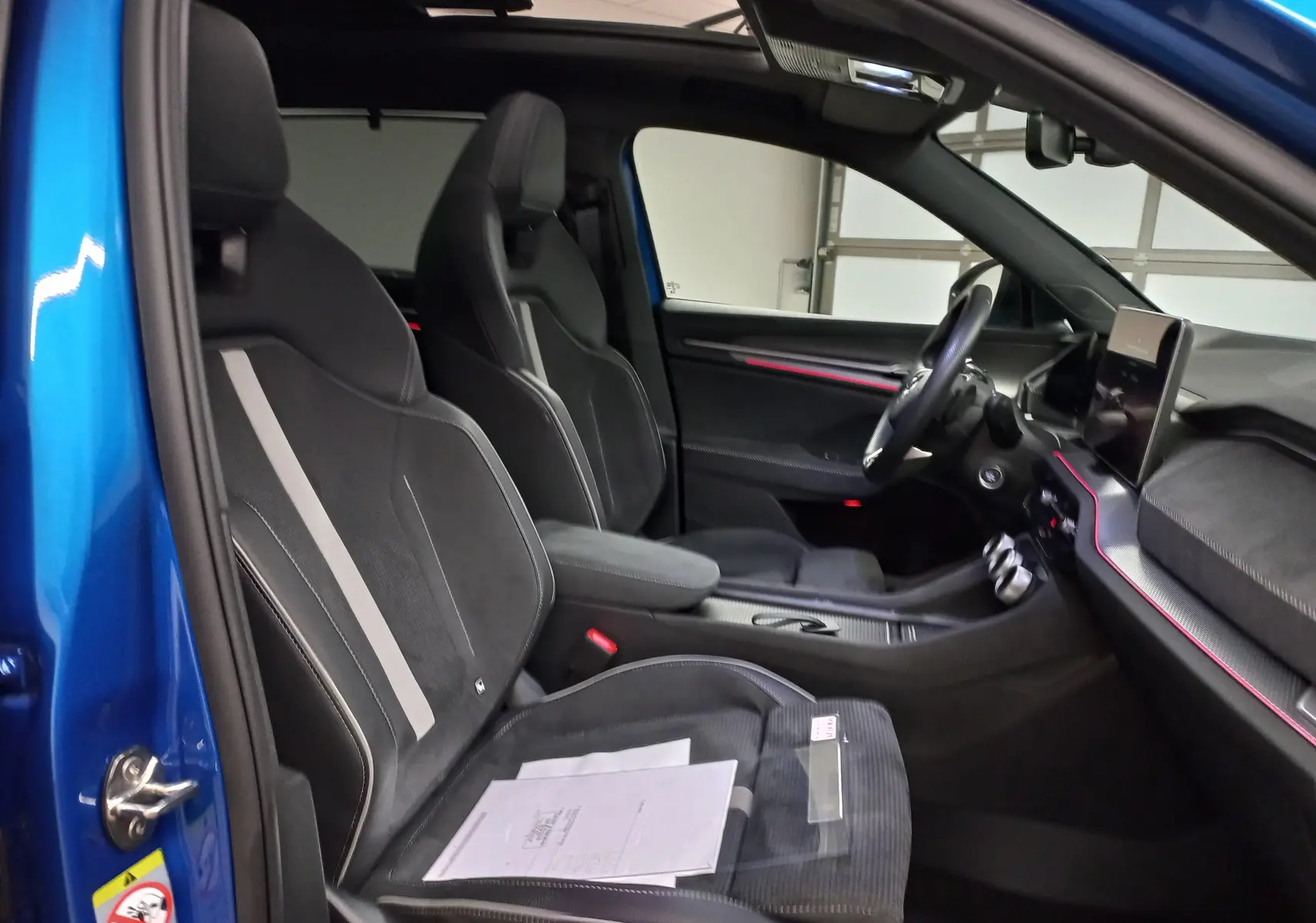 Vue intérieure côté conducteur du Skoda Kodiaq Bleu RS 2024, mettant en valeur les sièges sport noirs et le toit panoramique.