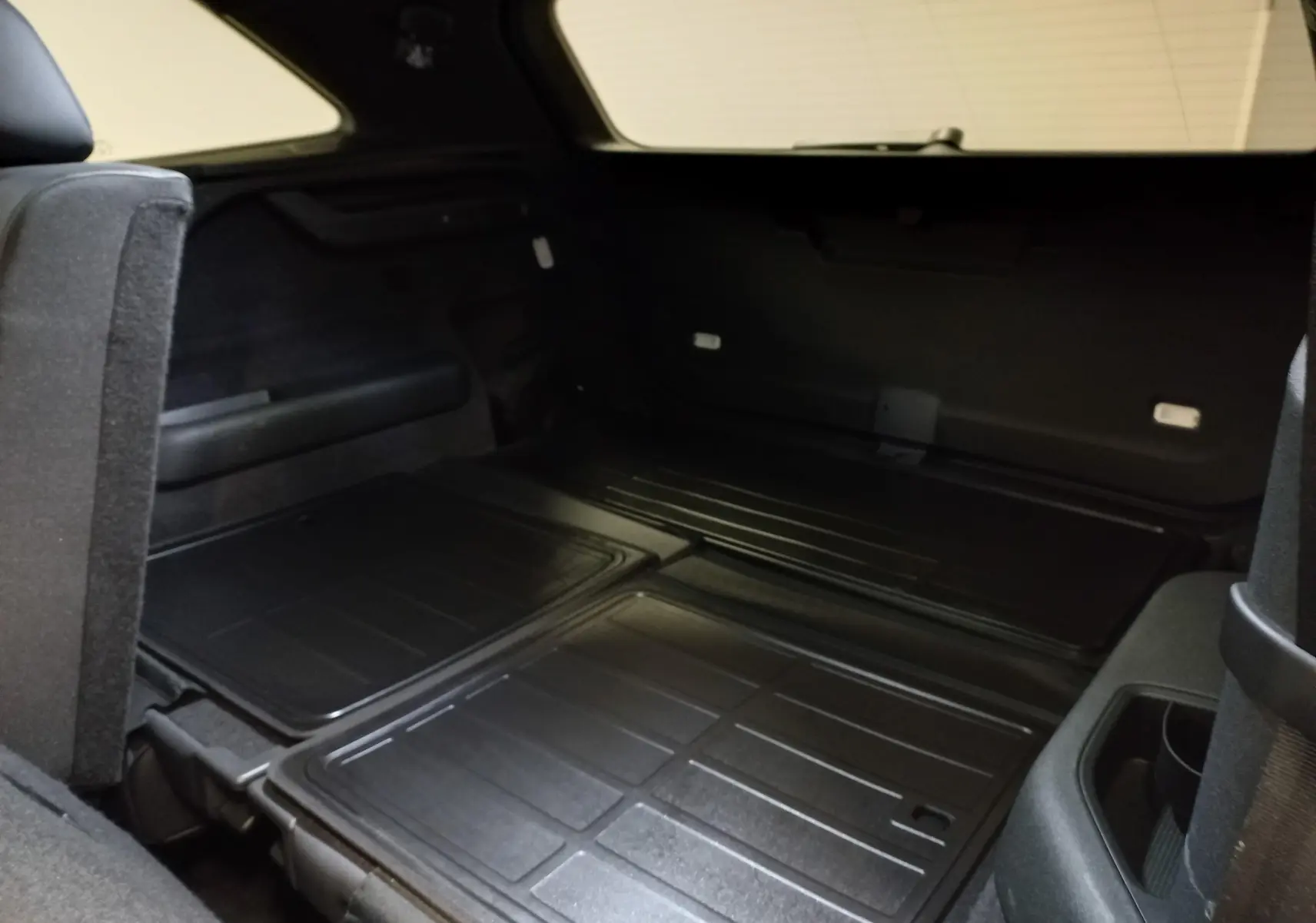 Vue intérieure du coffre du Skoda Kodiaq 2024 avec sièges arrière rabattus, montrant un espace de chargement plat et noir.