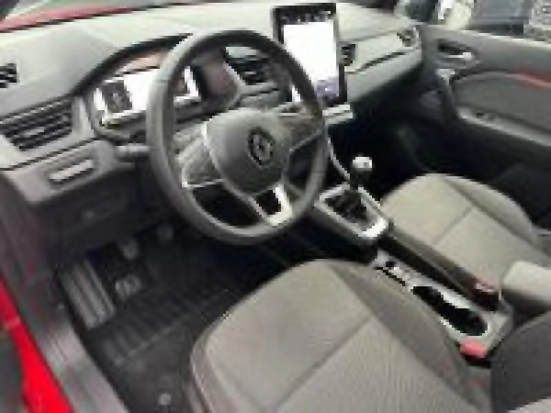 Vue intérieure côté conducteur du Renault Captur rouge 2025, volant multifonction et écran tactile vertical au centre.