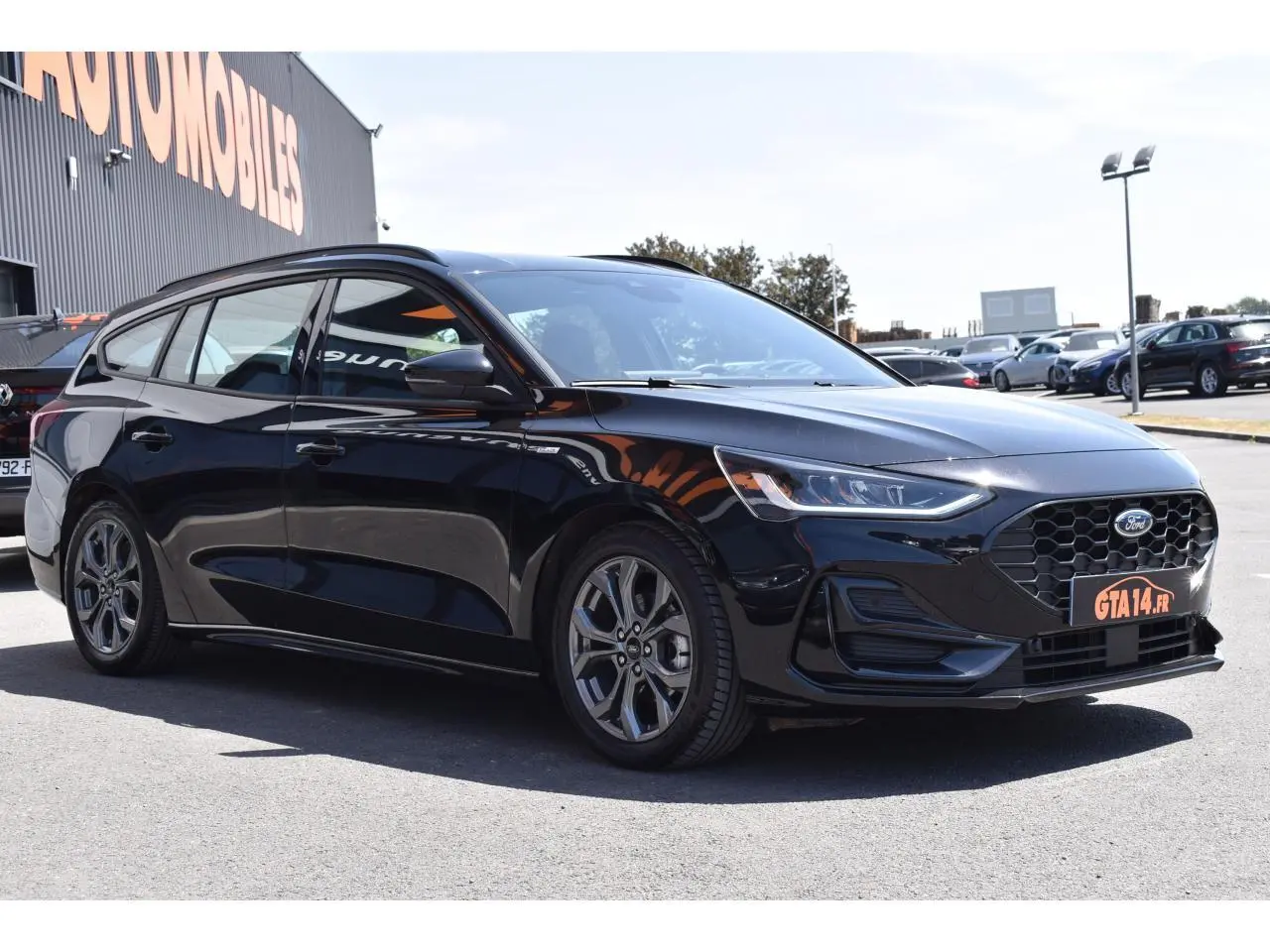 Ford Focus SW 1.5 EcoBlue 115 ST LINE X noir métallisé vue 3/4 avant droit, calandre hexagonale et jantes alliage visibles.