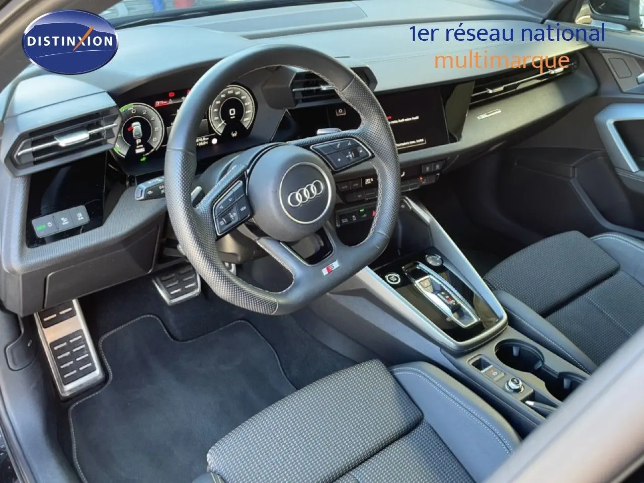 Vue intérieure côté conducteur de l'Audi A3 Sportback 40 TFSIe 2025, volant sport, tableau de bord digital et sellerie tissu noir.