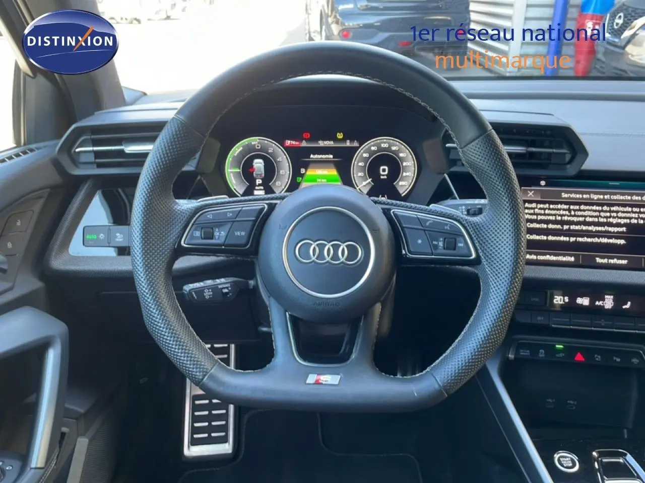 Vue intérieure centrée sur le volant sport perforé noir de l'Audi A3 Sportback 40 TFSIe 2025 avec tableau de bord digital.