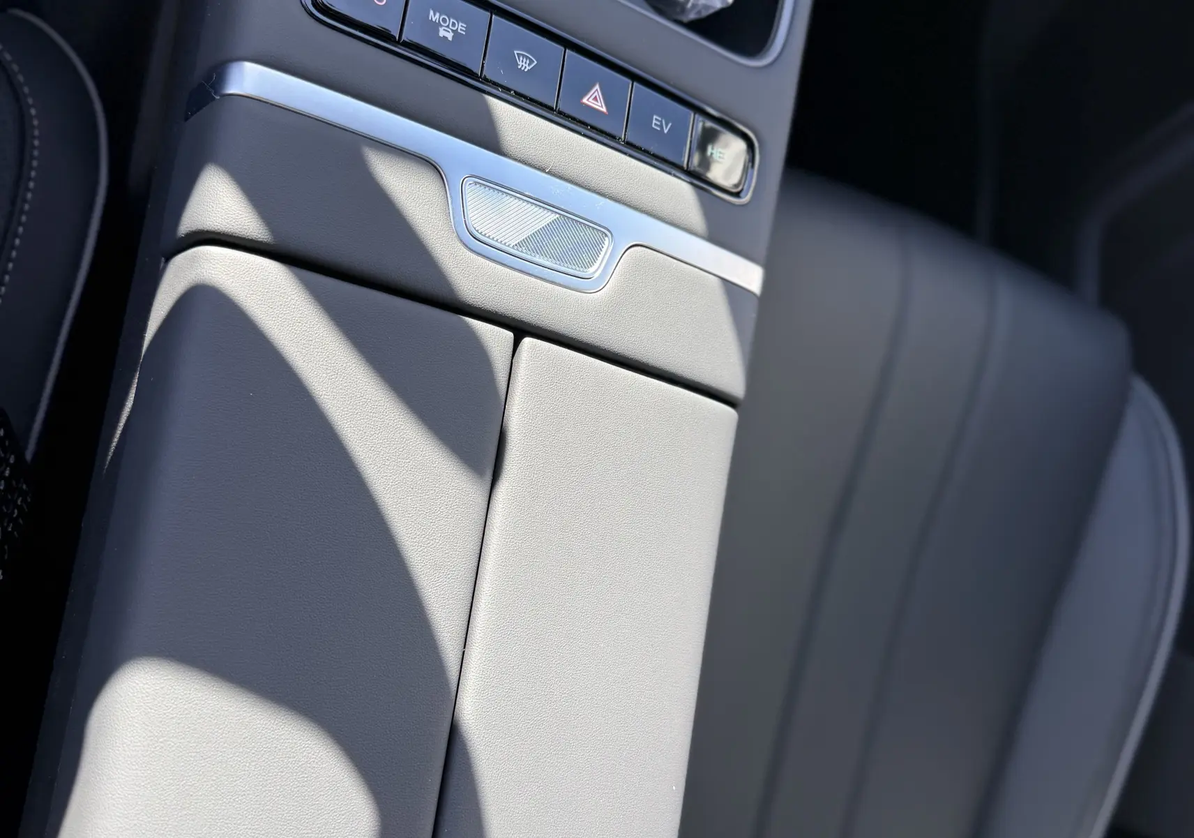 Vue rapprochée de la console centrale grise du JAECOO J7 PHEV 2026, avec boutons de commande et siège en cuir visible.