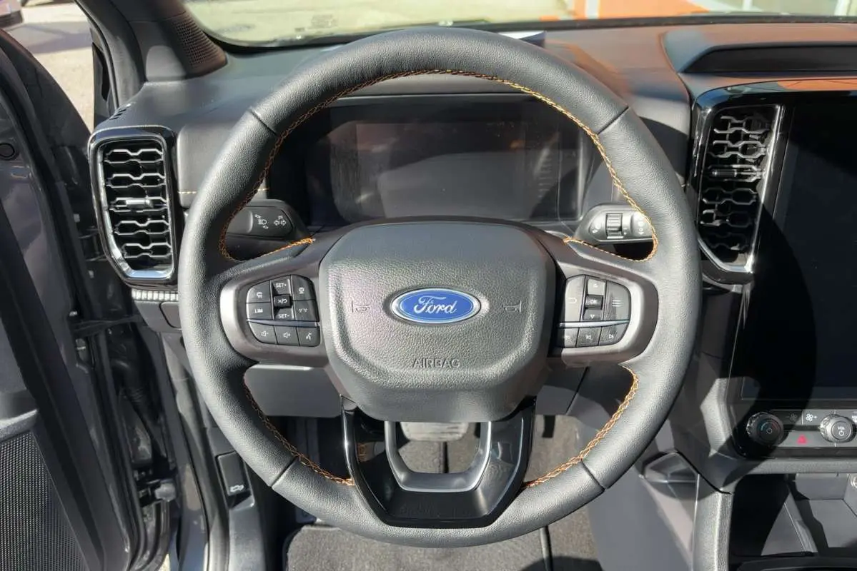 Vue rapprochée du volant cuir noir avec surpiqûres marron du Ford Ranger Wildtrak 2026, tableau de bord en arrière-plan.