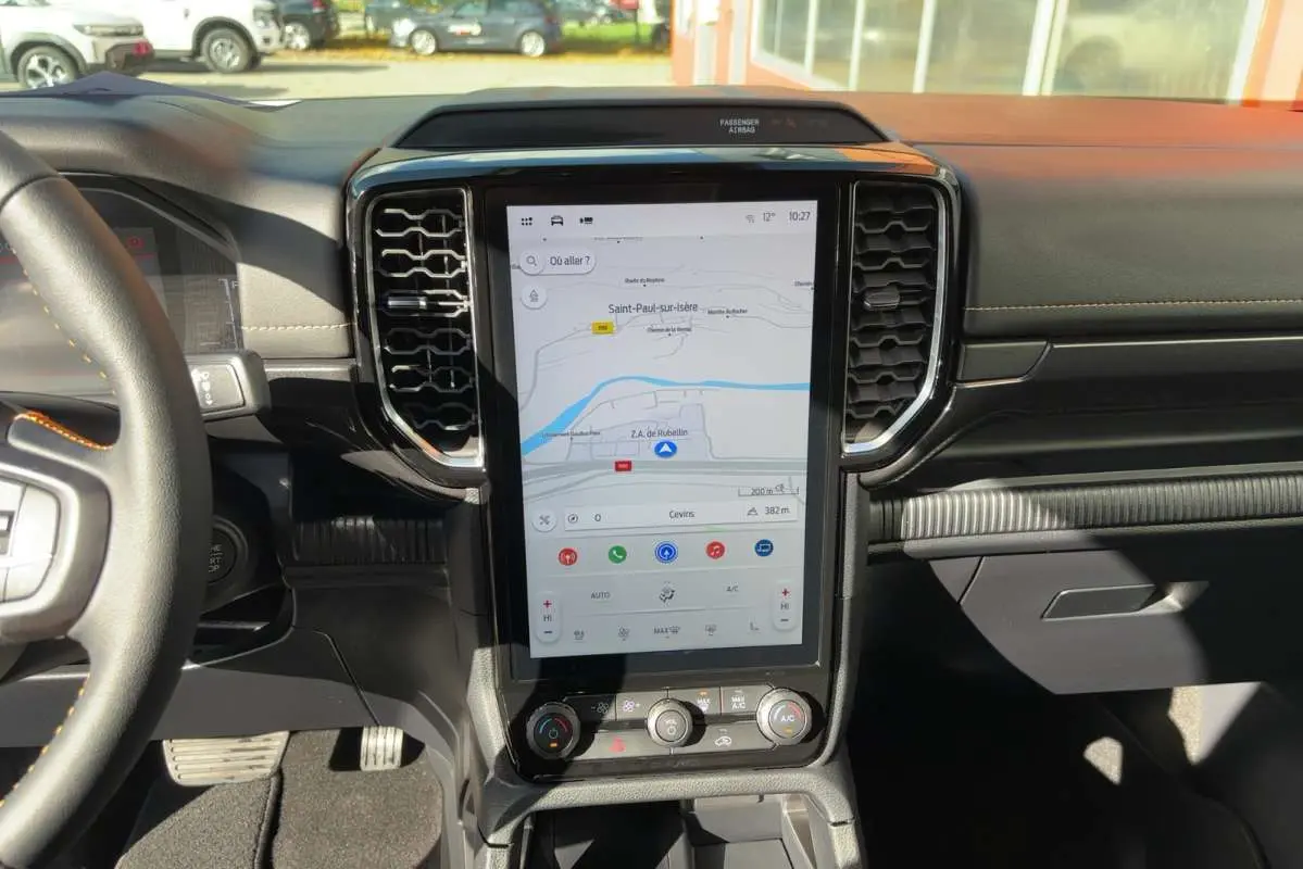 Vue intérieure centrée sur l’écran tactile vertical du Ford Ranger gris carbone avec tableau de bord noir et volant partiel.
