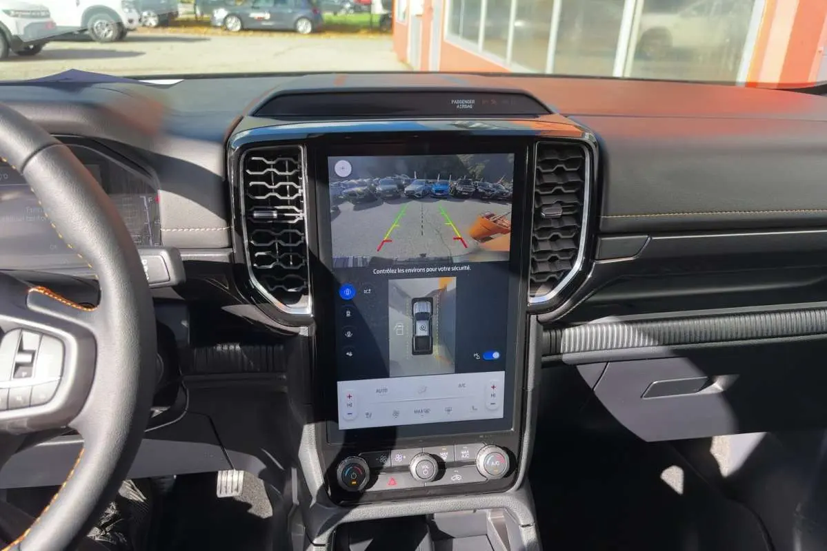 Vue intérieure du tableau de bord du Ford Ranger gris carbone 2026, avec écran tactile central affichant la caméra 360° et aides au stationnement.