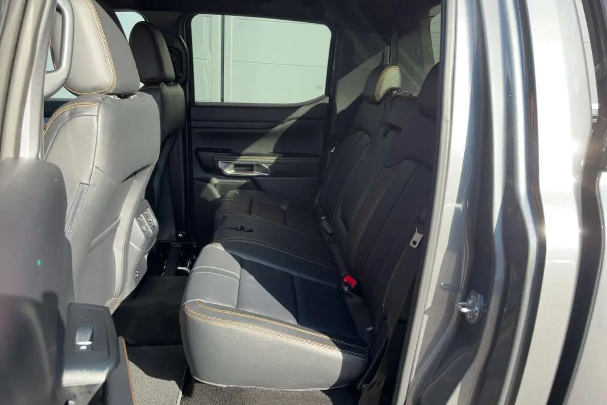 Vue intérieure côté droit des sièges arrière en cuir noir avec surpiqûres orange du Ford Ranger gris carbone 2026.