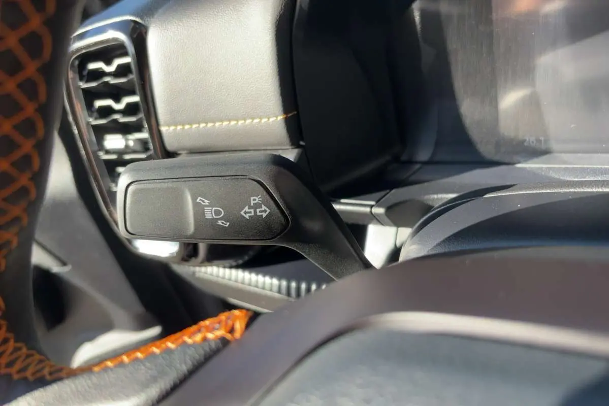 Gros plan sur la commande de clignotants à gauche du volant cuir noir avec surpiqûres orange du Ford Ranger gris carbone.