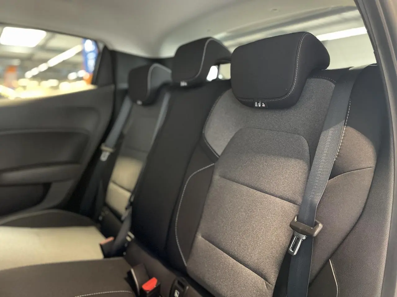 Vue intérieure du siège arrière droit de la Renault Clio 2025 avec sellerie tissu gris et ceinture de sécurité noire.