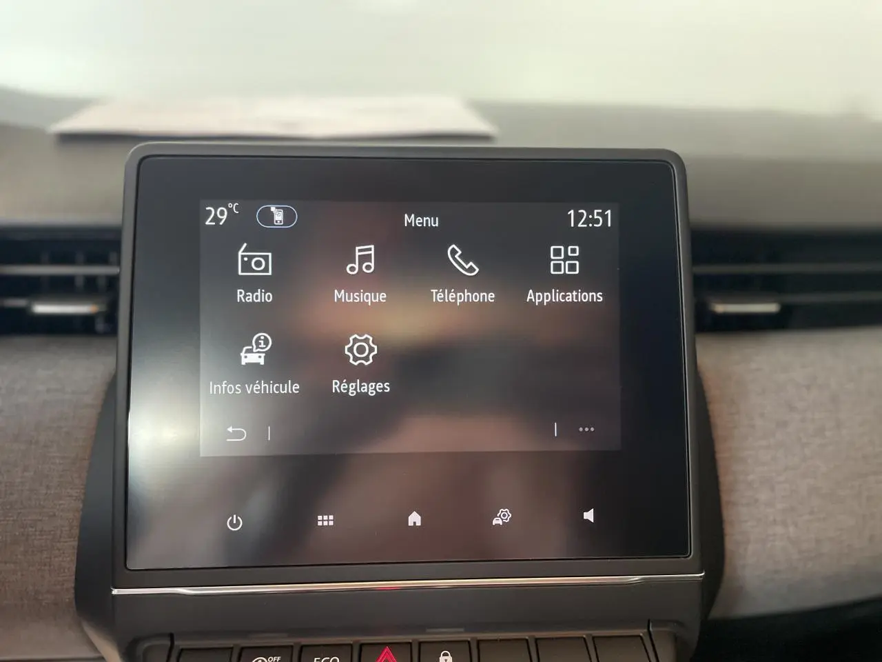 Écran tactile central de la Renault Clio 2025 avec menu principal et aérateurs latéraux chrome satiné visibles.