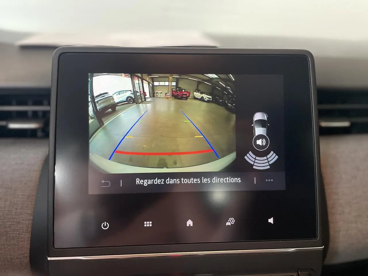 Écran tactile intérieur montrant la caméra de recul avec lignes de guidage sur Renault Clio blanc Glacier 2025.